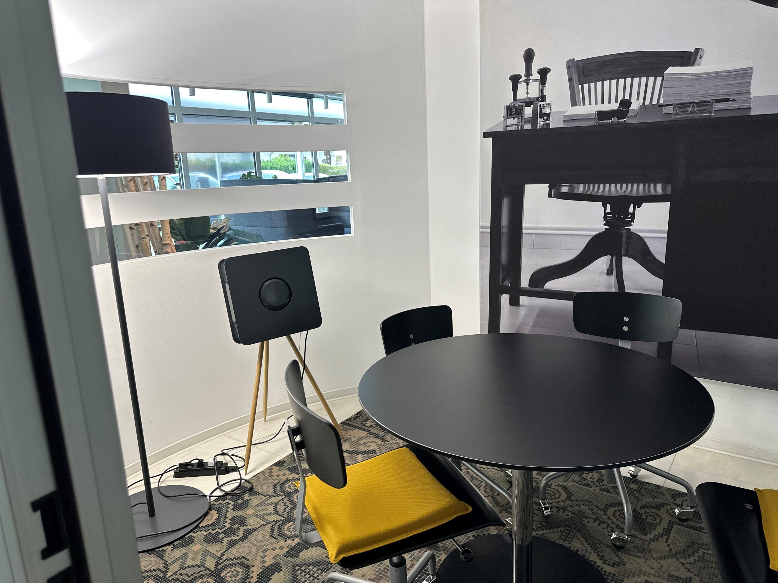 Een kleine kamer met een zwarte tafel met stoelen en een apparaat van BKE Health