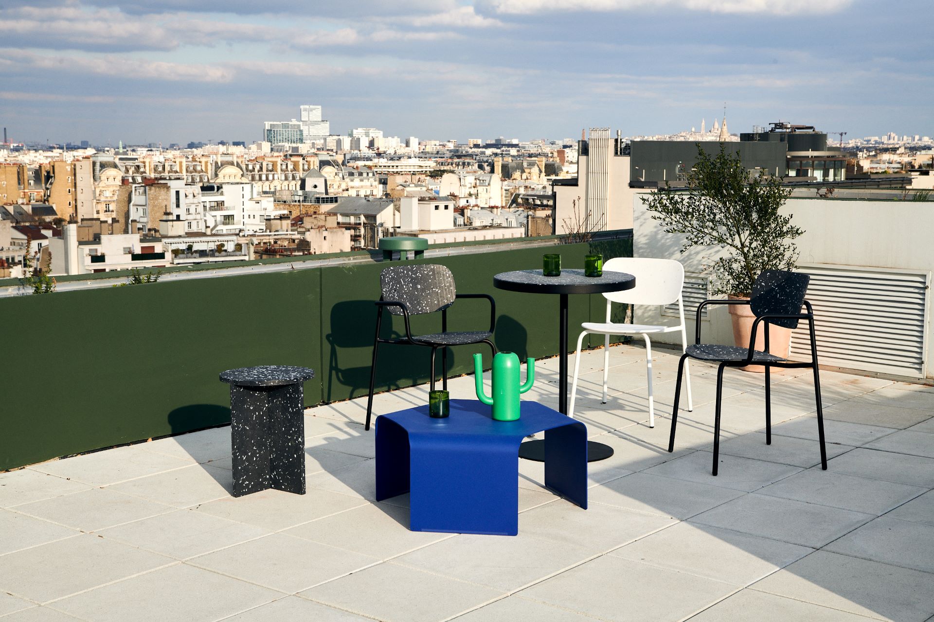 Stoelen en tafels op een roof top met uitzicht op de achtergrond. 