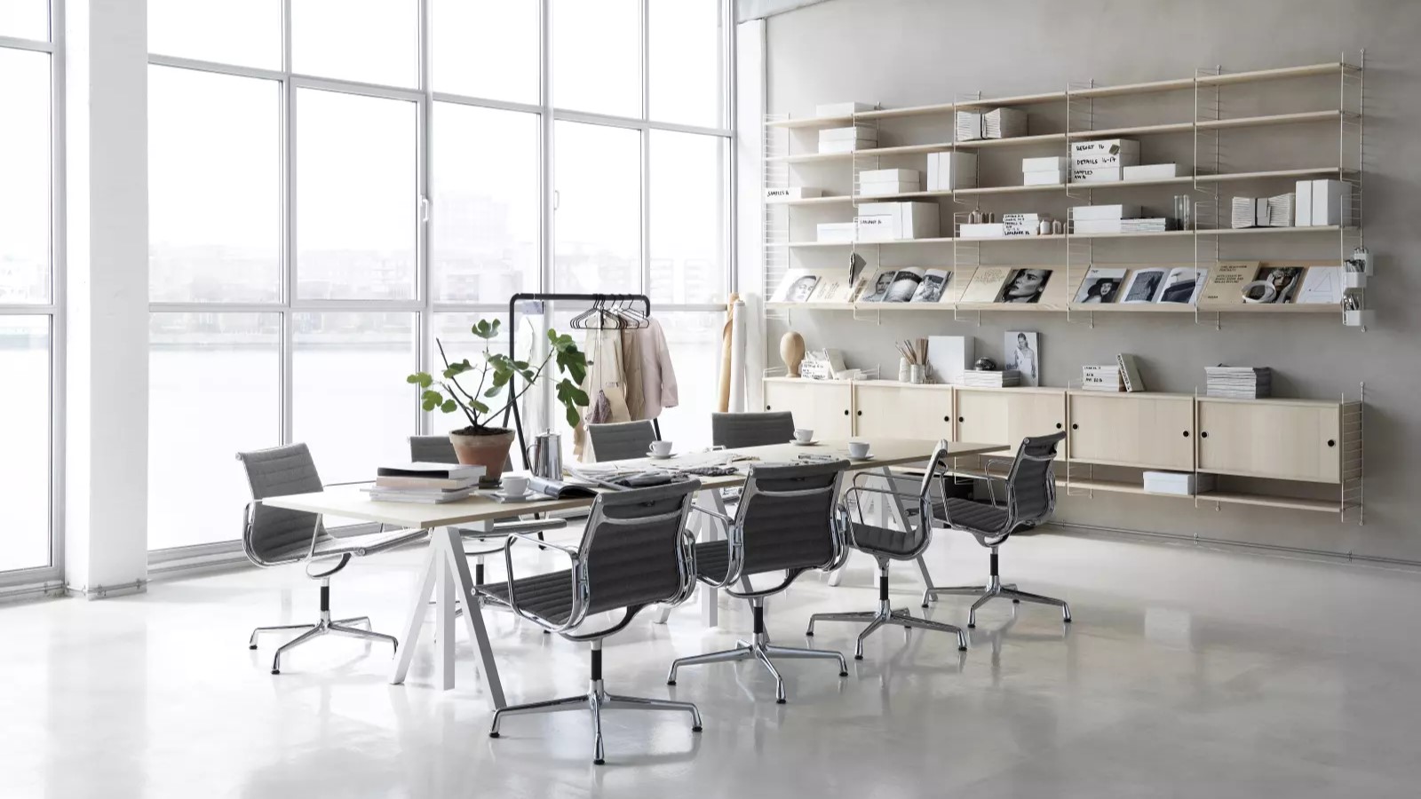 Een kantoor/vergader ruimte met een grote kast en tafel met meubilair van String Furniture