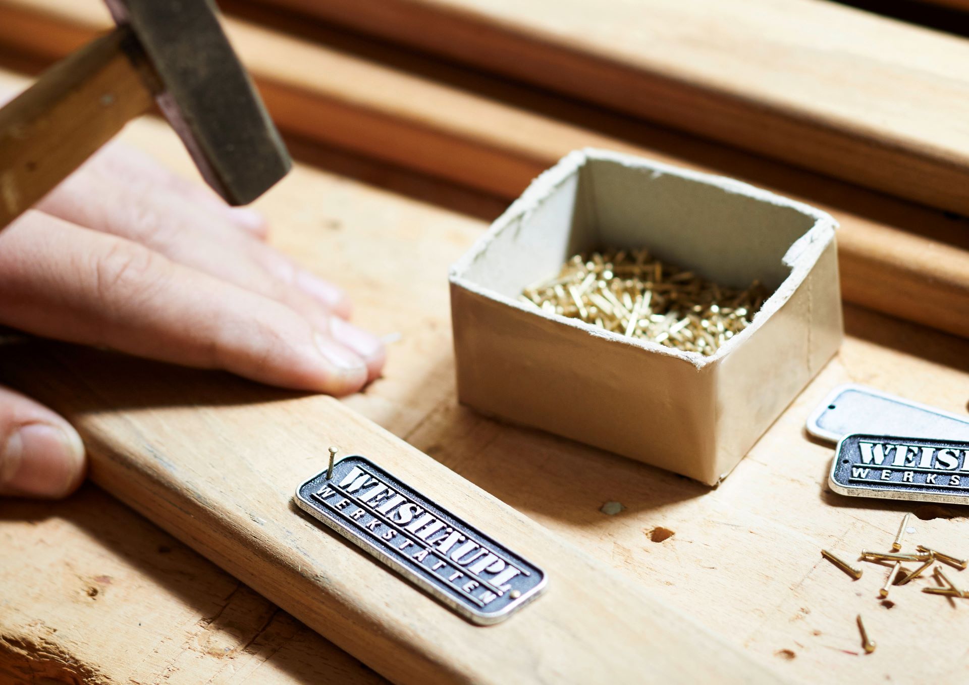 het logo van Weishäupl Möbelwerkstätten gedrukt op een houten balk