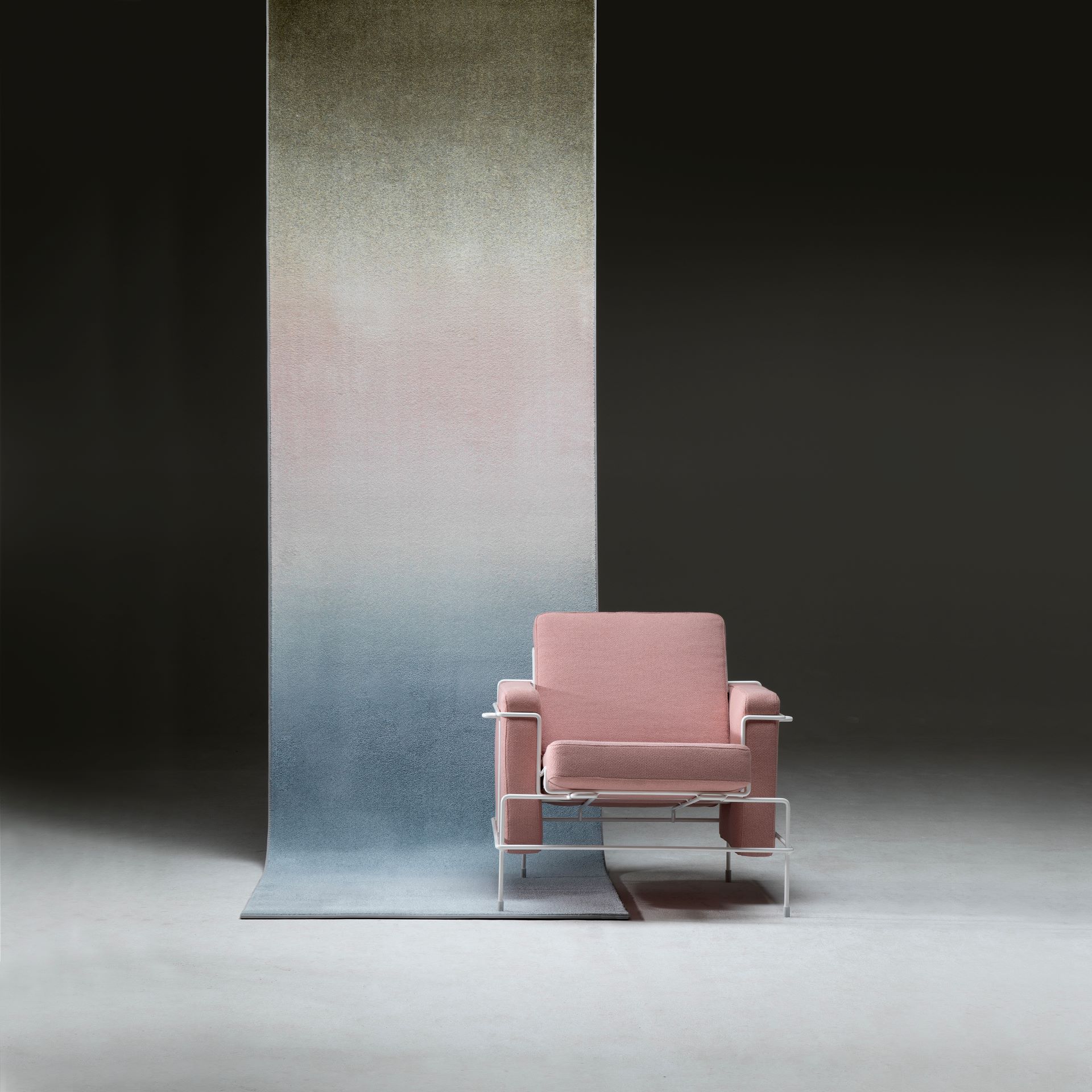 Roze/creme stoel midden in een donkere ruimte van Anker