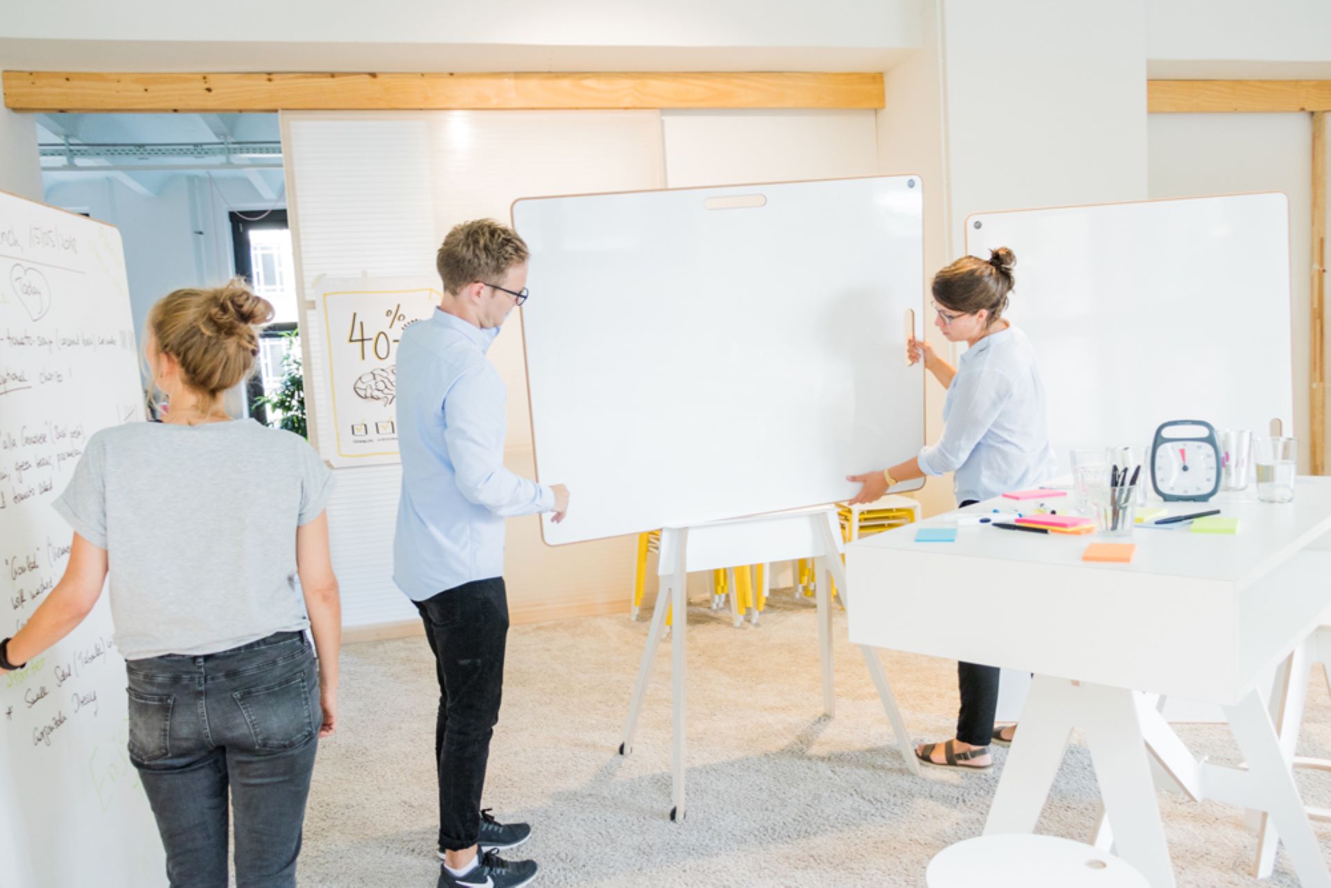 Drie werknemers die rondom een aantal whiteboards staan