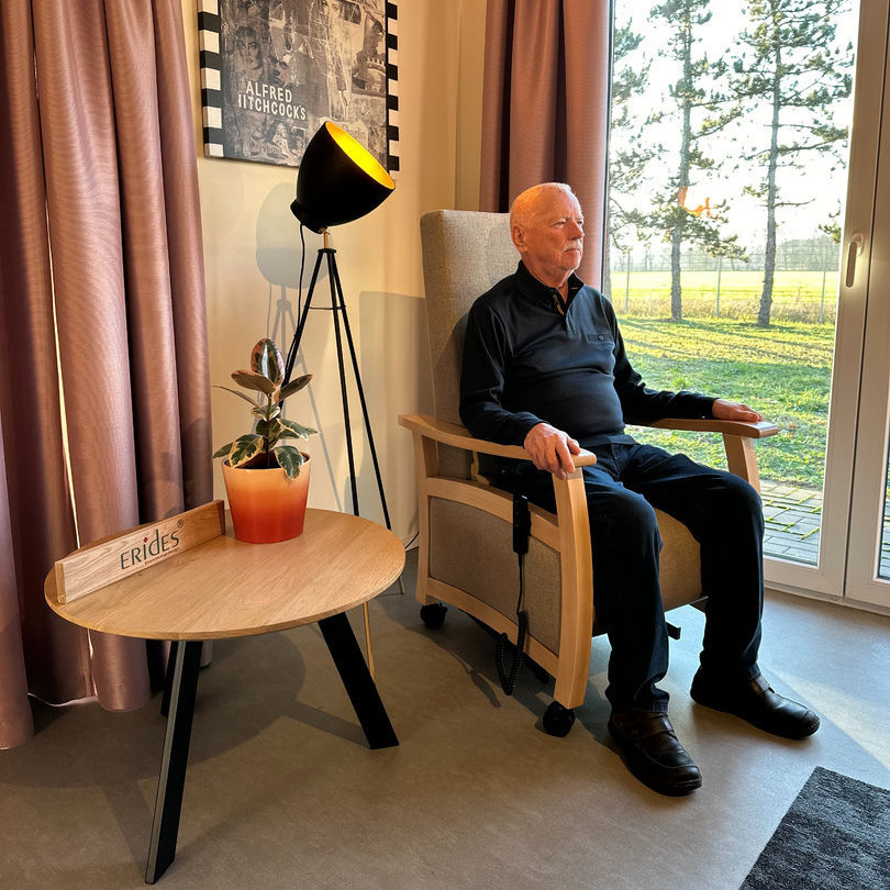 Zijaanzicht van een man die in een stoel van ERIDES Sitzmöbel zit voor een raam