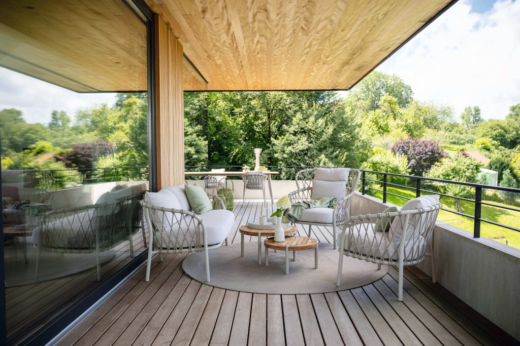 Vooraanzicht van een witte tuinmeubel aan de zijkant van een villa met uitzicht op veel bomen.