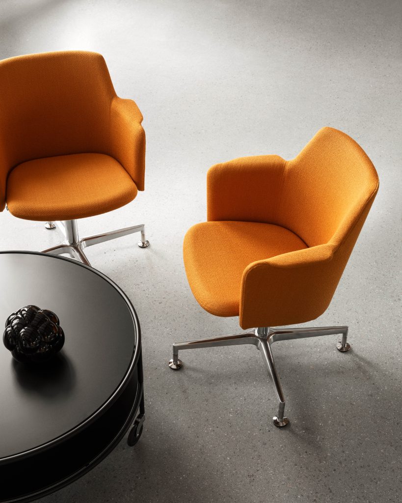 Grijze ruimte met een ronde grijze tafel en twee oranje stoelen van Lammhults