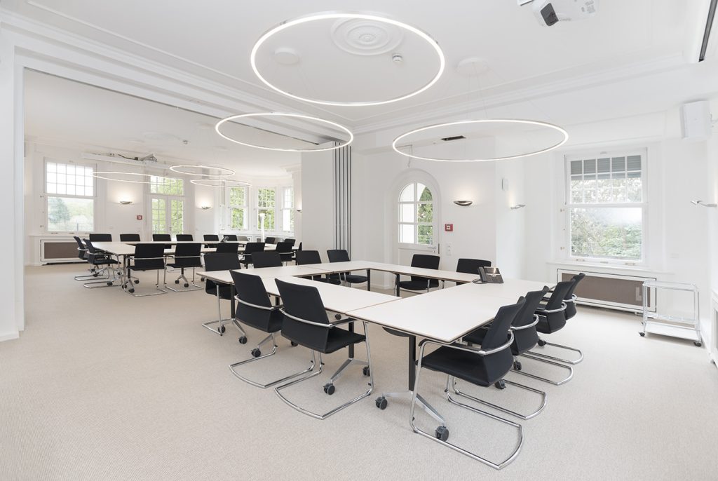 Witte kantoorruimte met witte tafels en vergaderstoelen