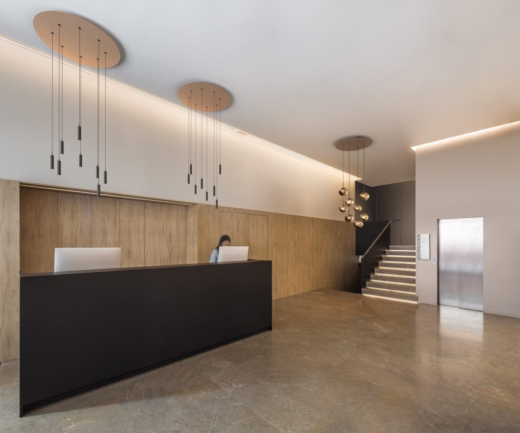 Hotellobby met zwarte balie, hout panelen wand en hanglampen van PROLICHT.