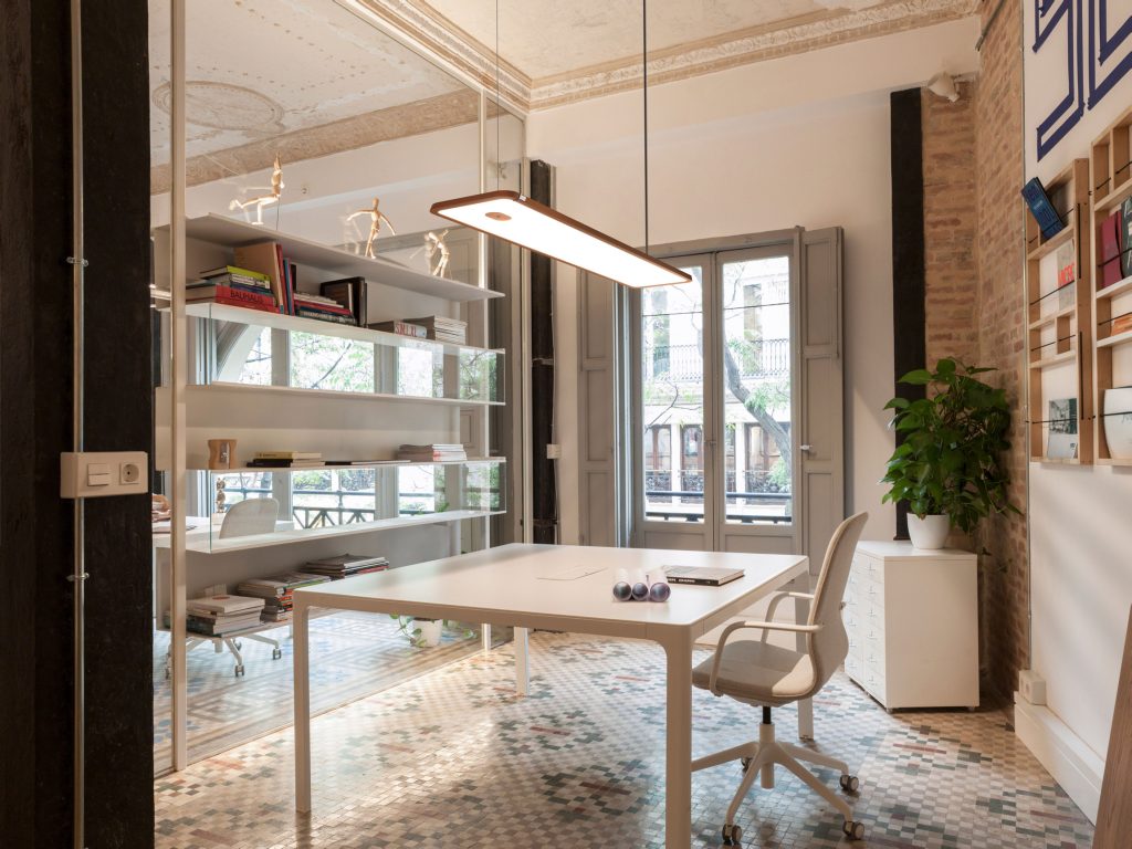 Witte kantoorruimte met bakstenen muur, tafel en bureaustoel