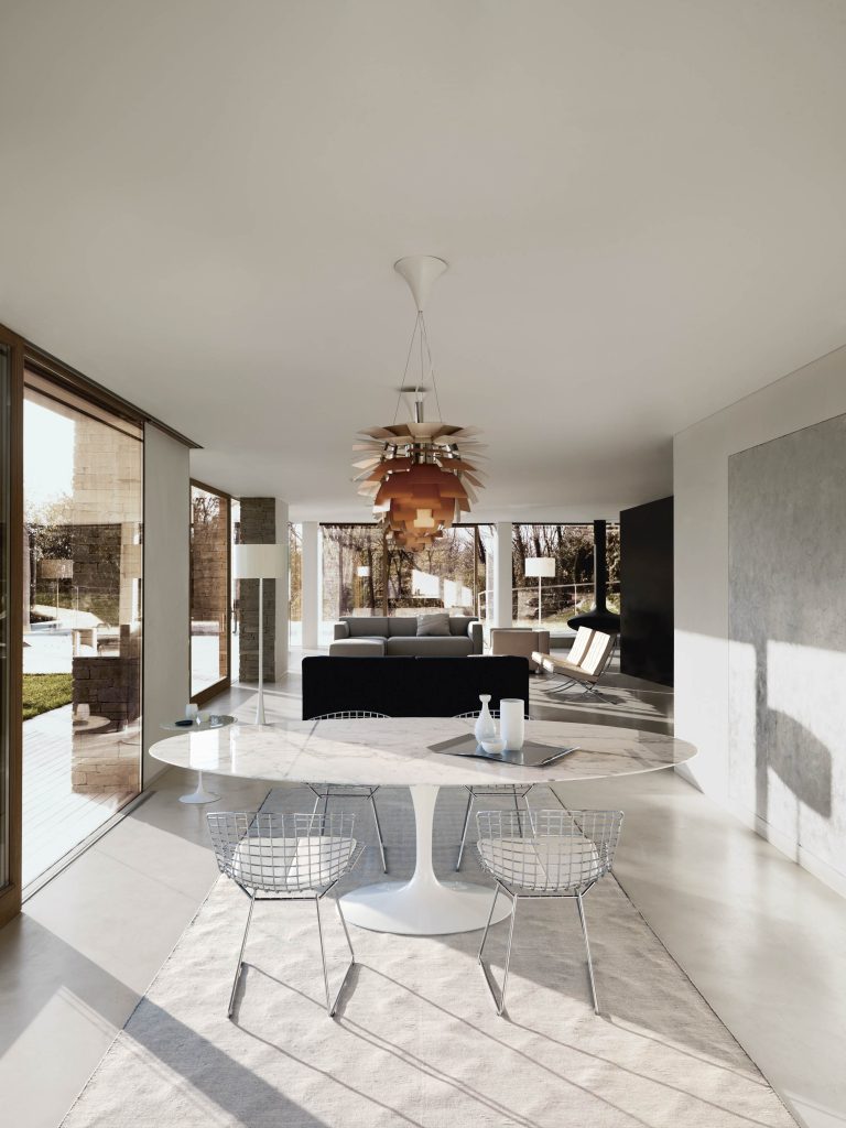 Witte ruimte met witte ronde tafel en stoelen en lamp van Knoll.