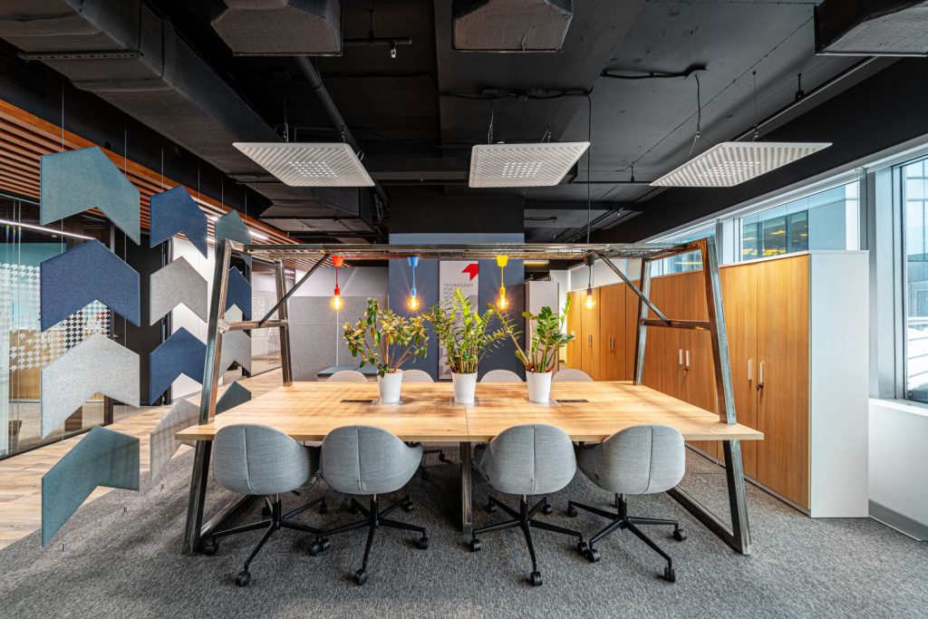 Zijaanzicht van een grote tafel met lampen eroverheen gespannen en stoelen van Furniko