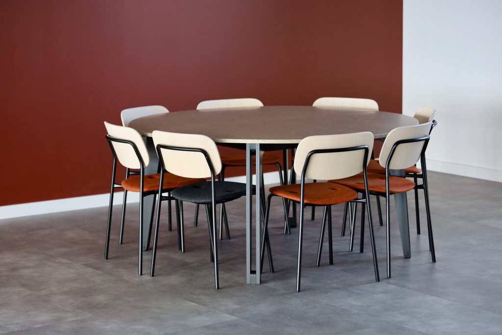 Lege ruimte met rode wand en tafel met stoelen van TIZU.
