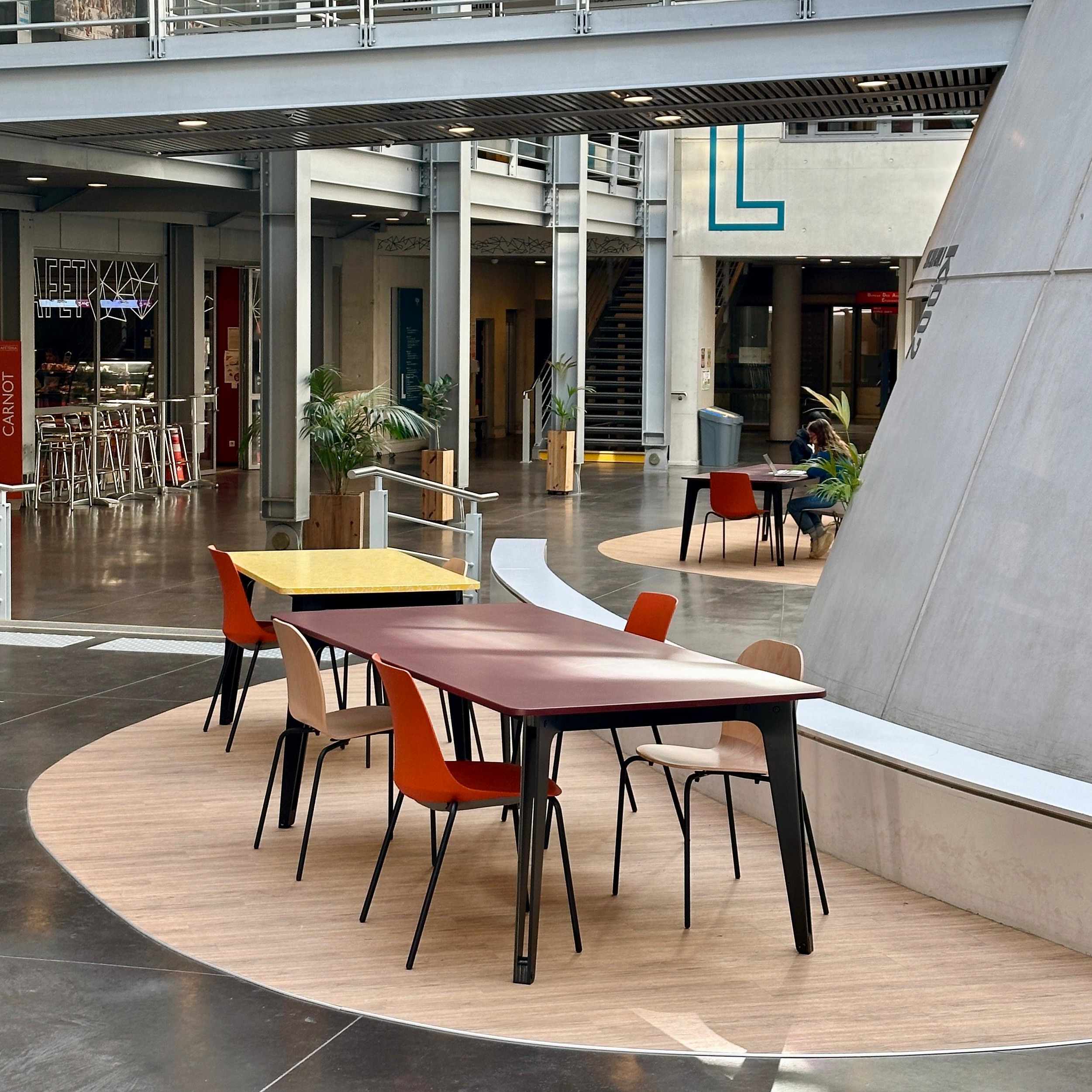 Open kantoorruimte/lunch kantine met lange tafel en rode, gele en bruine stoelen van TIZU.