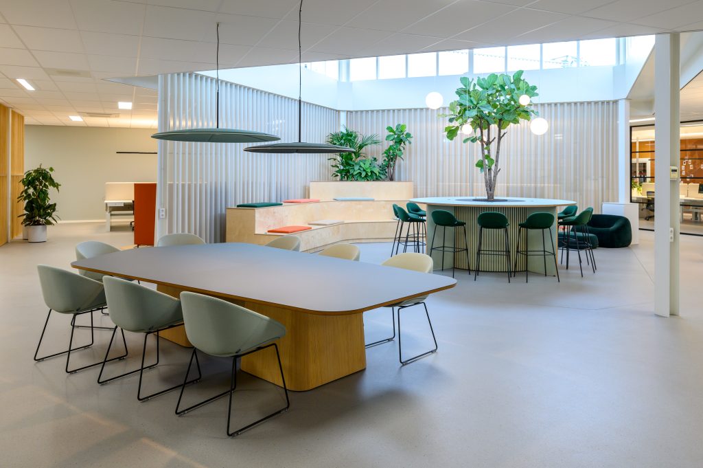 Kantoorruimte met in het midden een zithoek, ronde tafel en stoelen en lange tafel en stoelen van Lande.