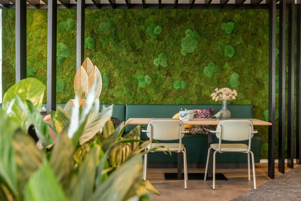 Groene moss wand met daarvoor een bank, tafel en twee stoelen van Lande.