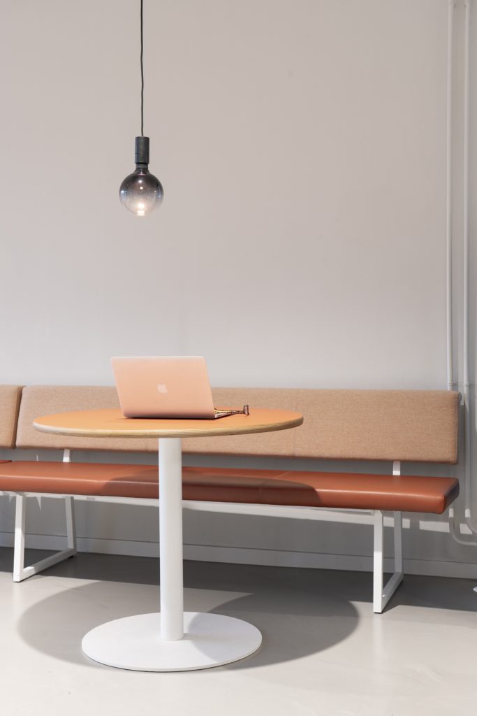 Vooraanzicht van een bank met ronde tafel, laptop en lamp.