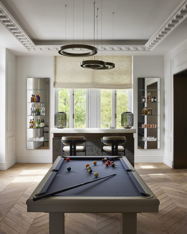 Grijze pooltafel midden in een witte kamer met lichten erboven