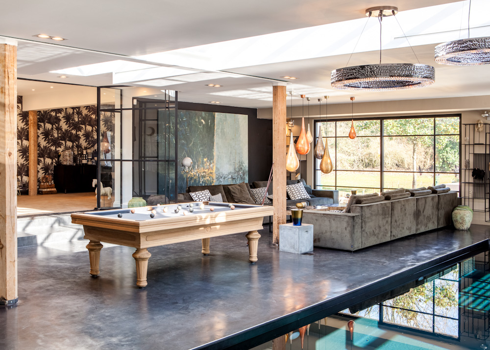 Grote luxe woonkamer met houtelementen en pooltafel in het midden