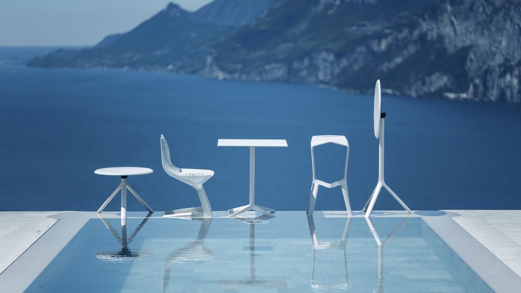 Een zwembad met verschillende witte stoelen van PLANK