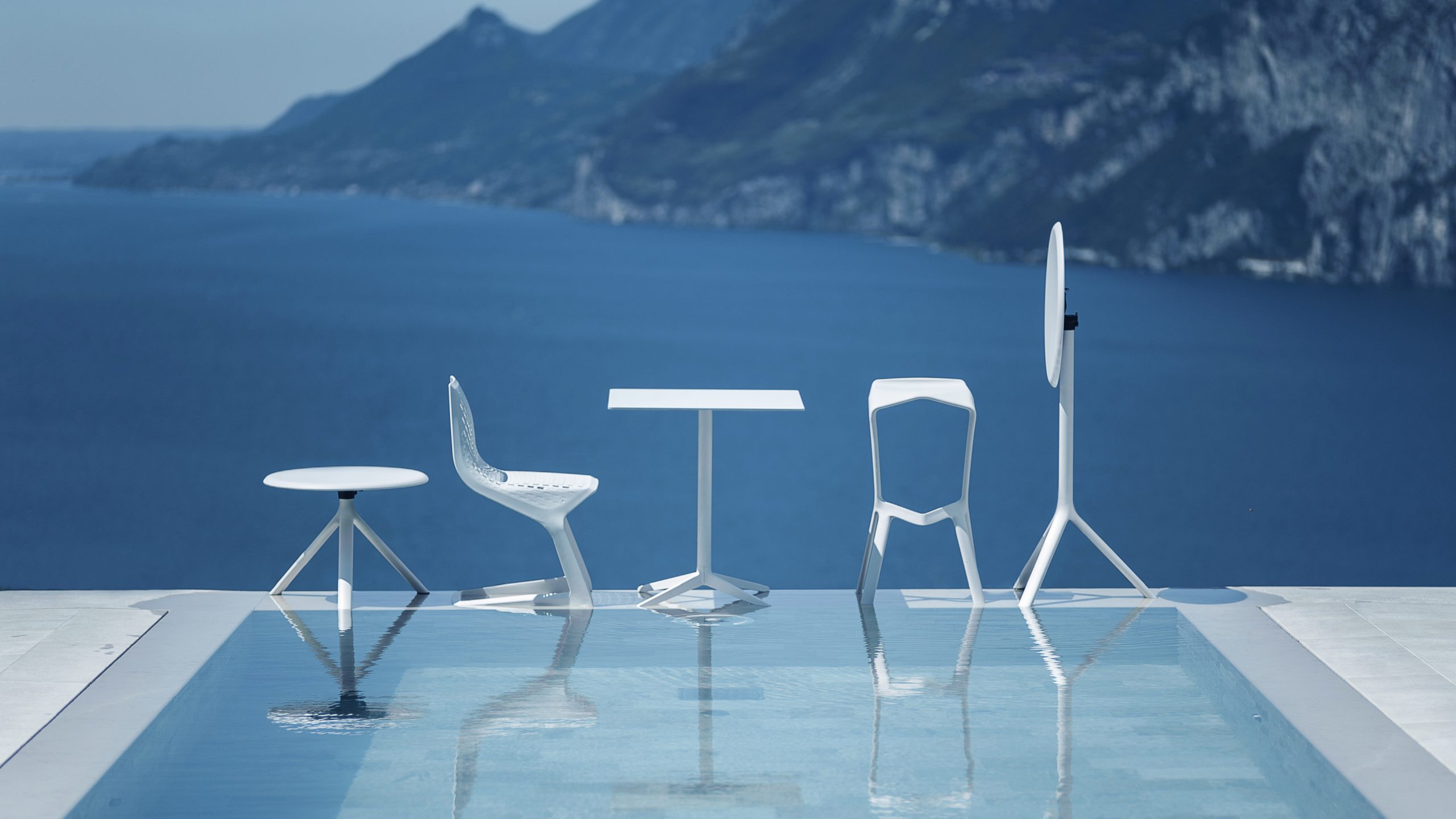 Een zwembad met verschillende witte stoelen van PLANK