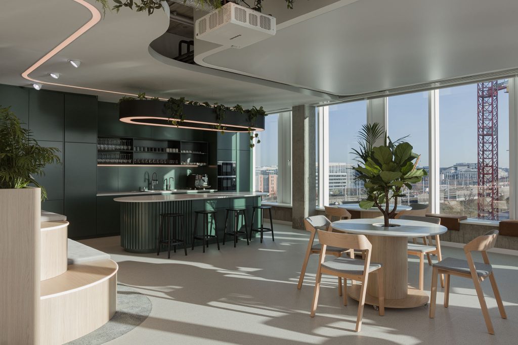 Een zijaanzicht van een moderne skyscraper appartement met keuken en ronde tafel met een boom erin met stoelen eromheen.