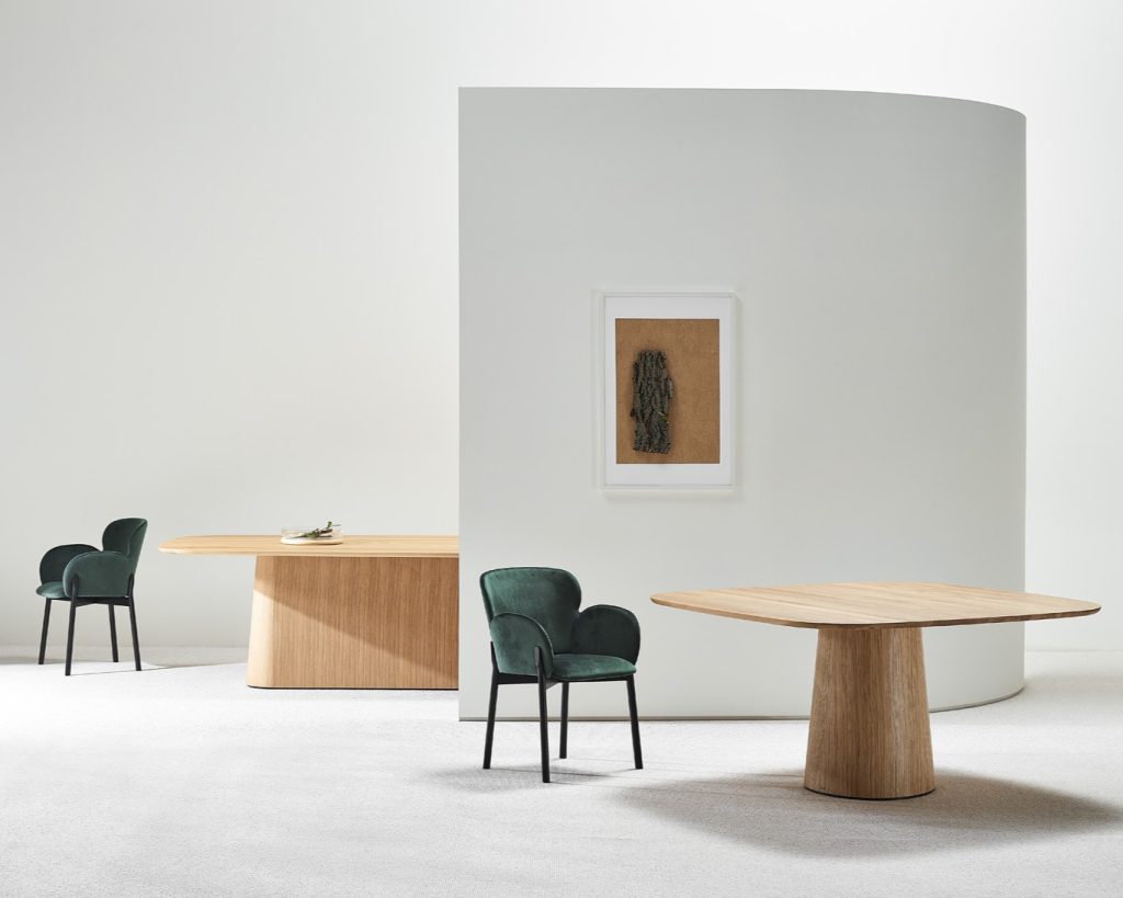 Een witte ruimte met een gebogen muurelement en tafels en stoelen van Ton.
