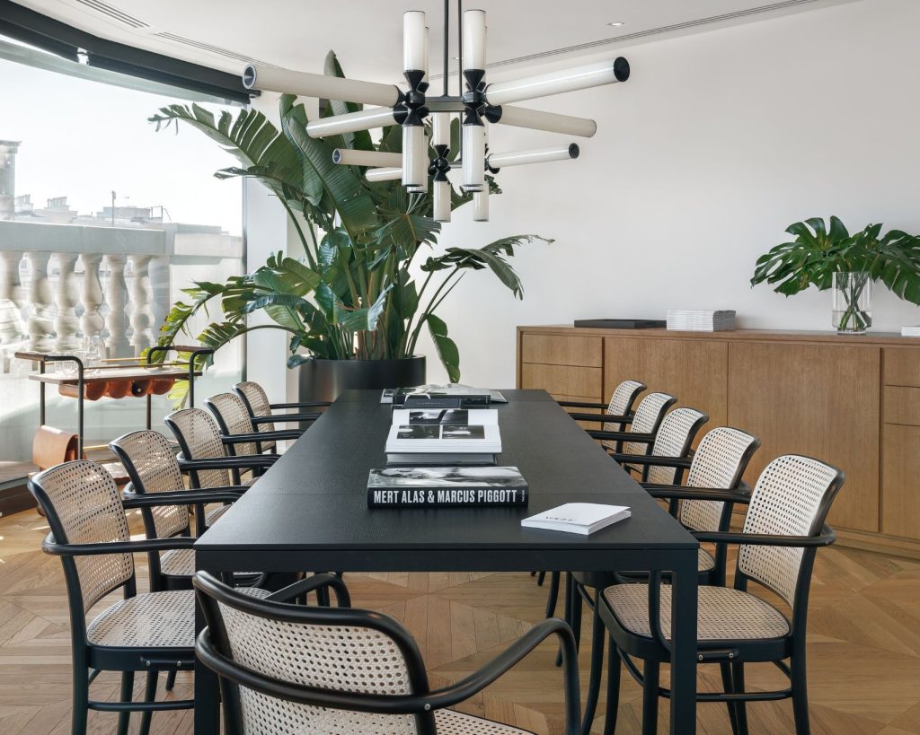 Vooraanzicht van een kamer met een lange zwarte tafel en stoelen eromheen.