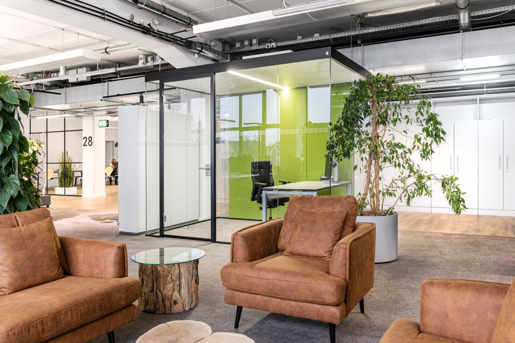 Een kantooromgeving met bruine leren banken en planten.