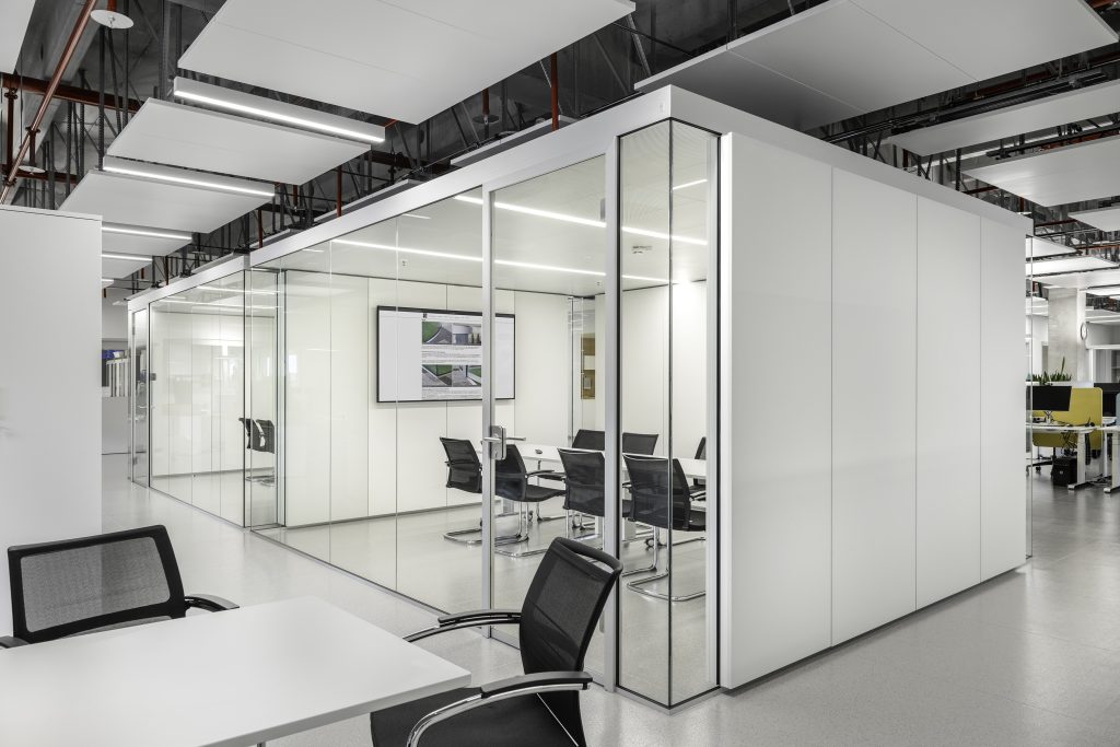 Witte kantooromgeving met witte tafels en zwart leren stoelen.