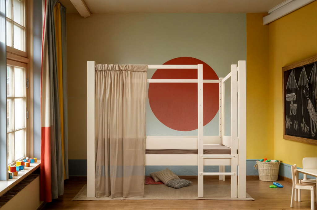 Vooraanzicht van een stapelbed van Wookids met licht houten frame en rode stip op de muur.
