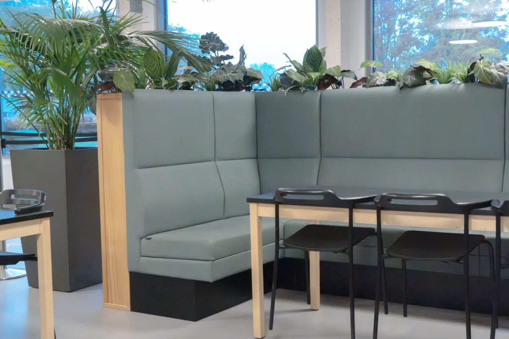 Een hoge blauw-grijze hoekbank rondom een tafel.