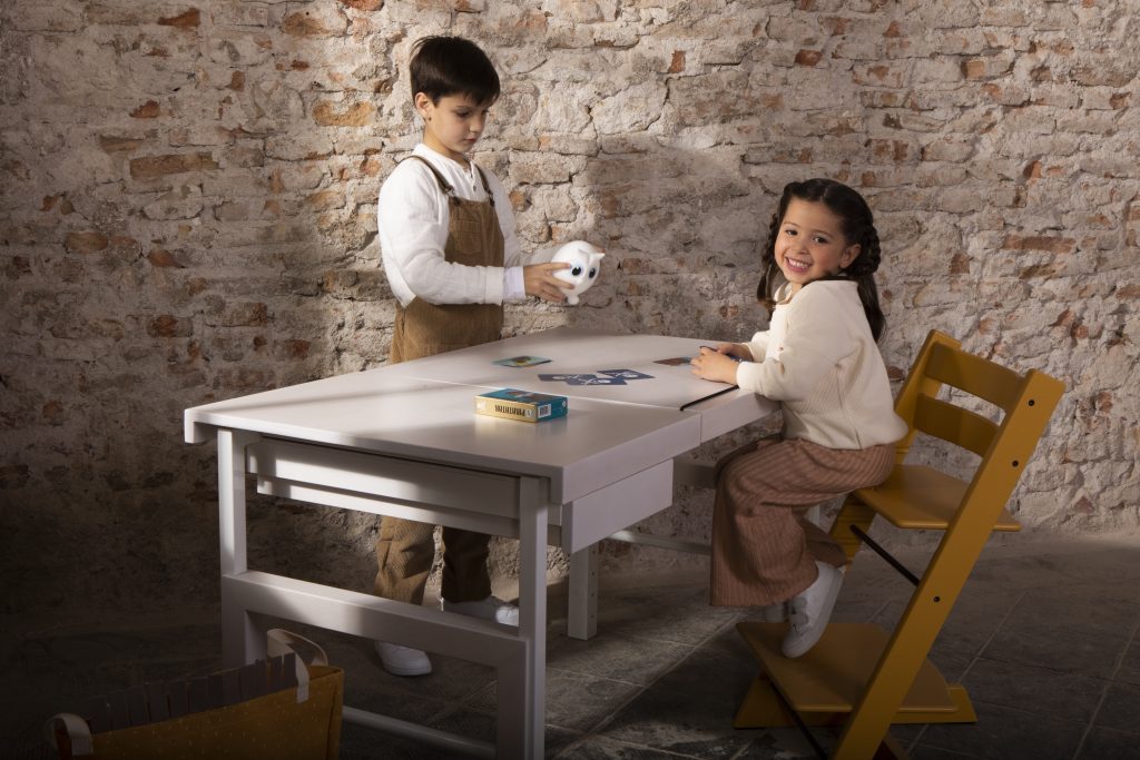 Zijaanzicht van een grijze speeltafel voor kinderen met 2 kinderen die spelen.