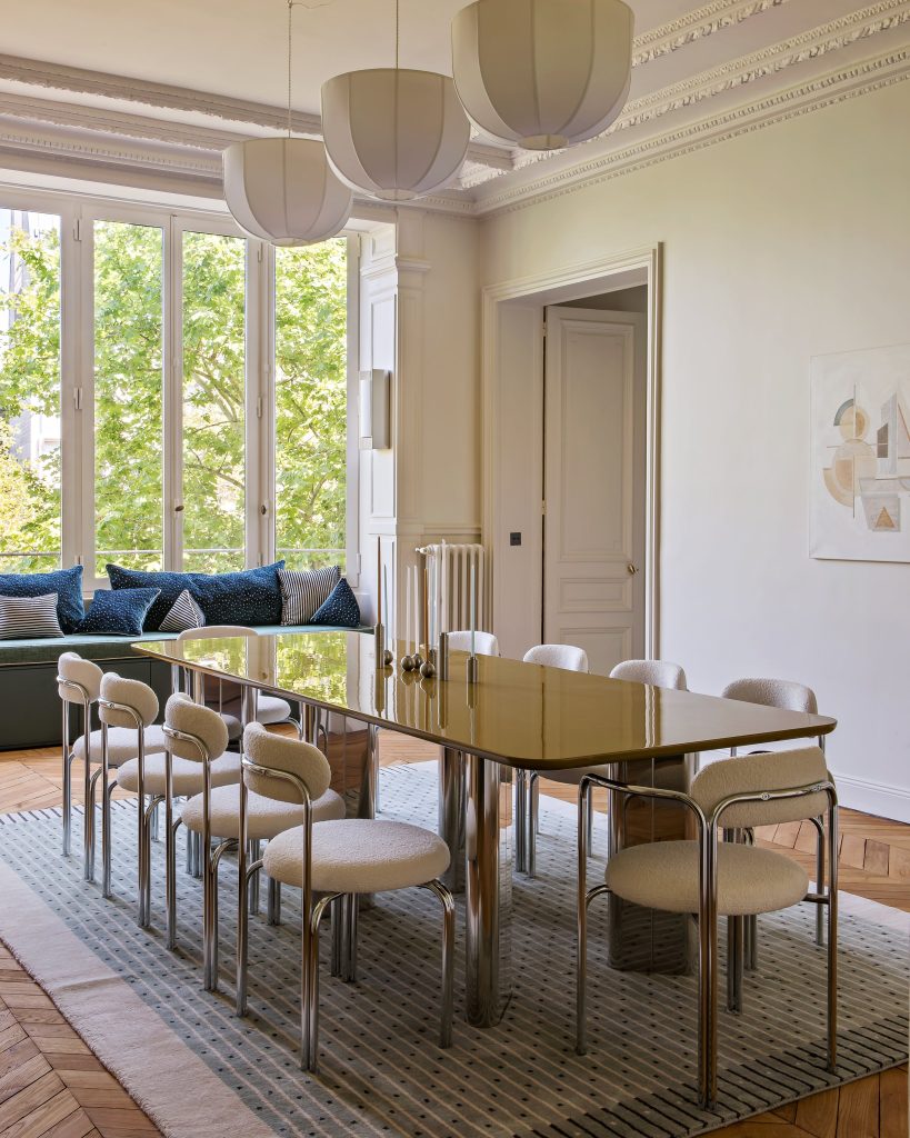Een zijaanzicht met een lange spiegeltafel met witte stoelen en witte lampen.