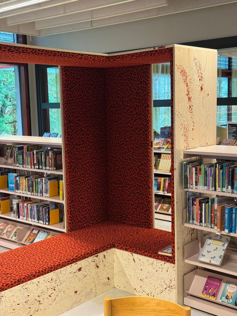 Ingebouwde rode zitbank in een boekenkast van een bibliotheek.